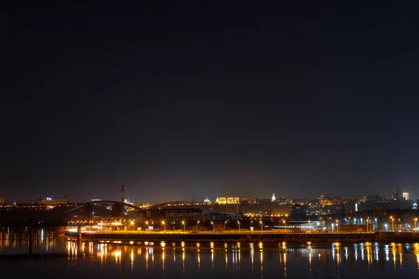 Paesaggio urbano tranquillo con edifici illuminati e riflessione sul fiume di notte — Foto stock