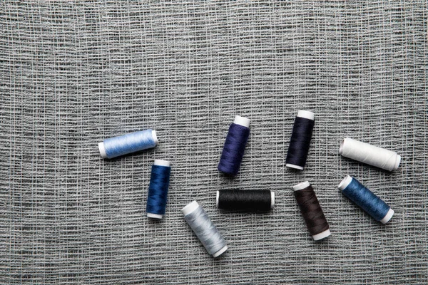 Top view of scattered blue and grey thread coils on sackcloth with copy space — Stock Photo