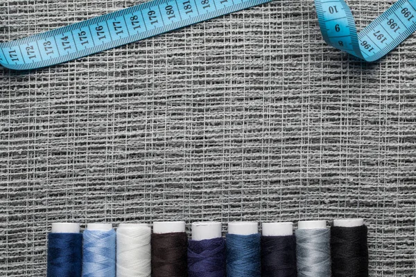 Top view of blue and grey thread coils on sackcloth with measuring tape and copy space — Stock Photo