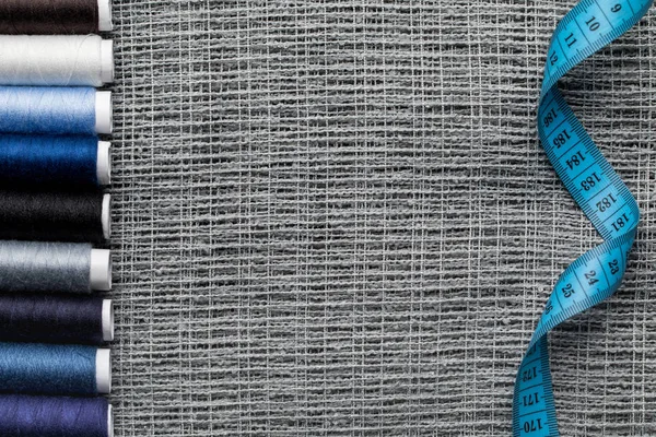 Top view of blue and grey thread coils on sackcloth with measuring tape and copy space — Stock Photo