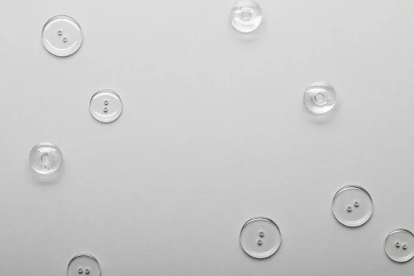 Top view of transparent clothing buttons isolated on grey with copy space — Stock Photo