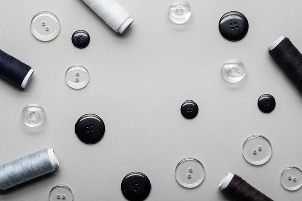 Vista superior de botones de ropa y bobinas de rosca aisladas en gris - foto de stock