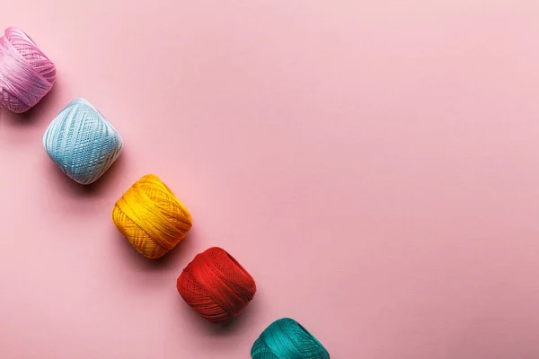 Top view of arranged colorful cotton knitting yarn balls on pink with copy space — Stock Photo