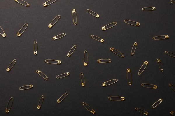 Top view of scattered metal safety pins isolated on black — Stock Photo