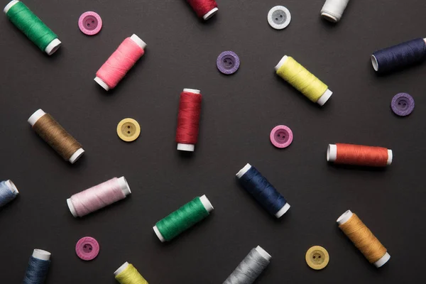 Top view of colorful thread coils with various buttons isolated on black — Stock Photo