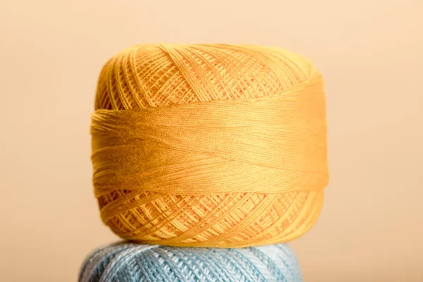 Ball of yellow cotton knitting yarn ball isolated on beige — Stock Photo