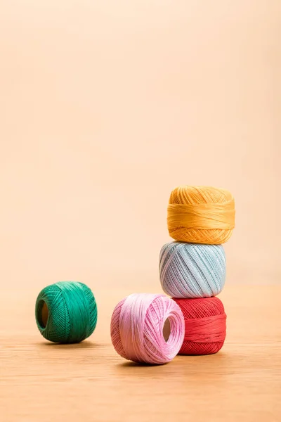 Colorati batuffoli di filato di cotone a maglia su tavolo di legno isolato su beige con spazio copia — Foto stock