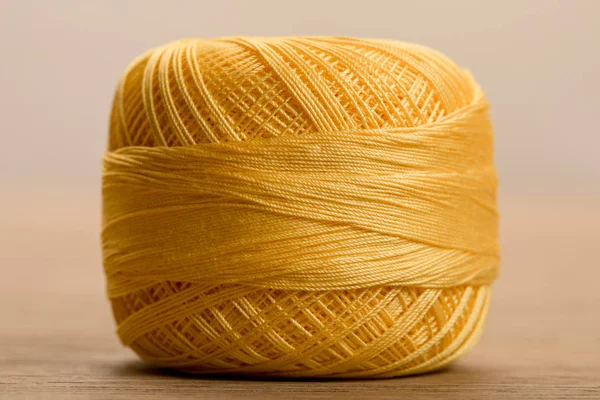 Close up view of yellow cotton knitting yarn ball on beige — Stock Photo