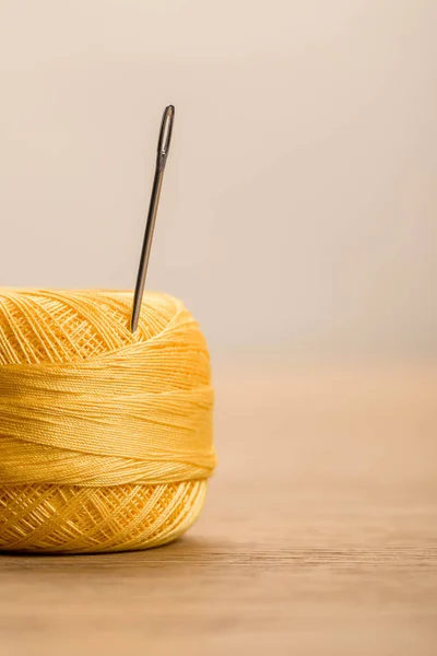 Selective focus of yellow cotton knitting yarn ball with needle isolated on beige with copy space — Stock Photo