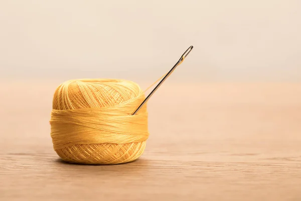 Selective focus of yellow cotton knitting yarn ball with needle isolated on beige with copy space — Stock Photo