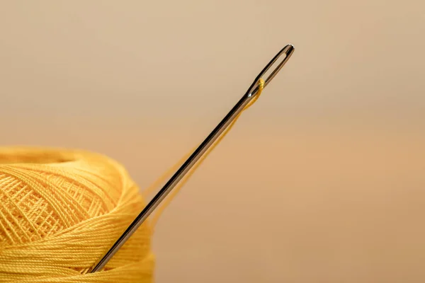 Selective focus of yellow cotton knitting yarn ball on beige with copy space — Stock Photo