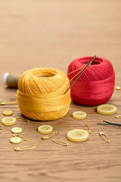 Baumwollstrickgarnbällchen mit Kleidungsknöpfen und Sicherheitsnadeln auf Holztisch — Stockfoto