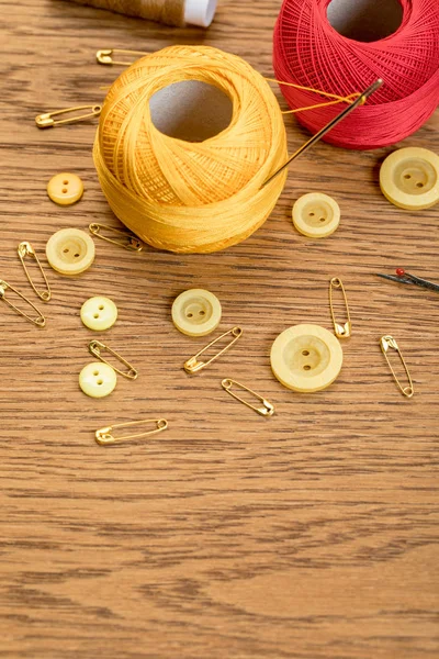 Bolas de fio de tricô de algodão com botões de roupa e alfinetes de segurança na mesa de madeira com espaço de cópia — Fotografia de Stock
