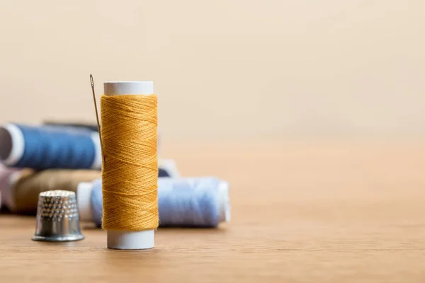 Enfoque selectivo de bobina de hilo de algodón con aguja aislada en beige con espacio de copia - foto de stock