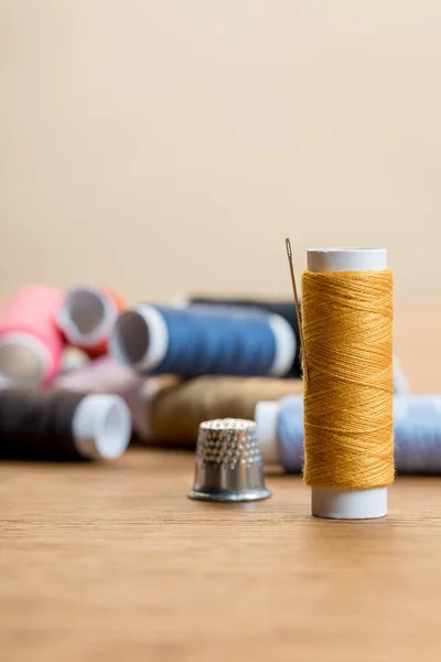 Foco seletivo da bobina de fio de algodão com agulha isolada em bege com espaço de cópia — Fotografia de Stock