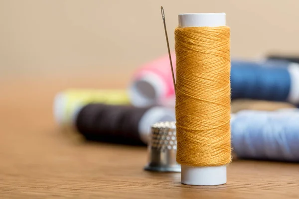 Selective focus of thread coil with needle on table isolated on beige with copy space — Stock Photo