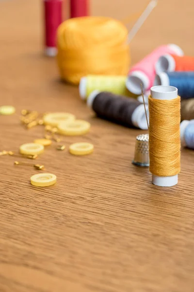 Foco seletivo de bobina de fio dedal e amarelo com agulha na mesa de madeira com espaço de cópia — Fotografia de Stock