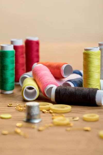 Selective focus of colorful thread coils, safety pins and buttons isolated on beige — Stock Photo