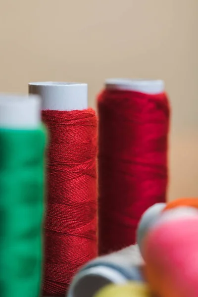 Enfoque selectivo de bobinas de hilo de algodón rojo aisladas en beige - foto de stock