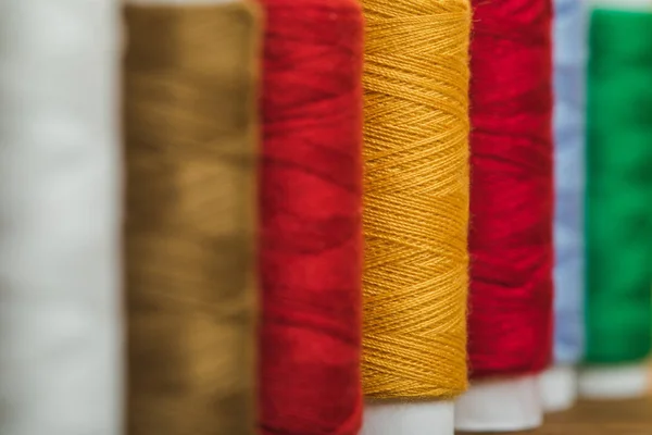 Selektiver Fokus bunter Baumwollfadenspulen in Reihe mit Kopierraum — Stockfoto