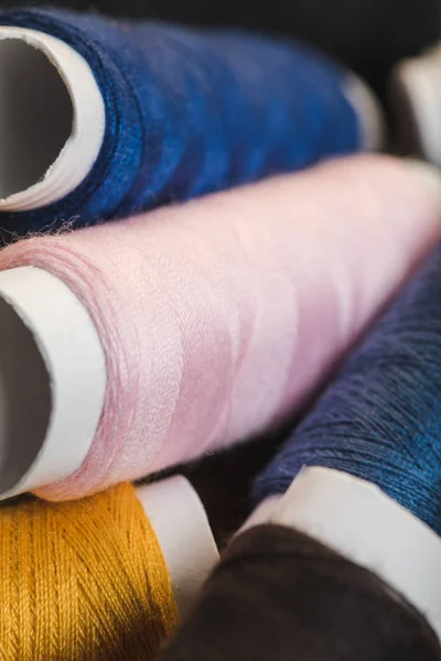 Vista de cerca de las bobinas de hilo de algodón rosa, azul y amarillo - foto de stock