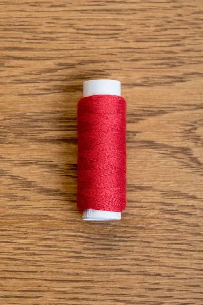 Top view of red cotton thread coil on wooden surface — Stock Photo