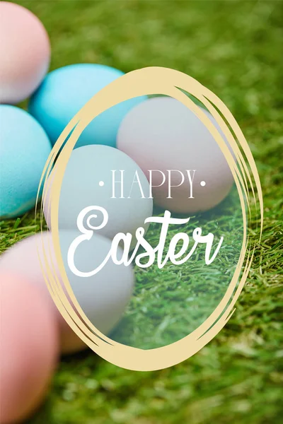 Pile of multicolored painted chicken eggs with happy Easter lettering on green grass — Stock Photo