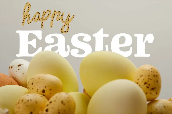 Yellow painted eggs with happy Easter lettering on grey background — Stock Photo