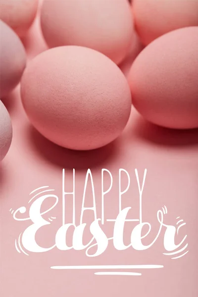 Painted pink eggs on pink surface with happy Easter lettering — Stock Photo