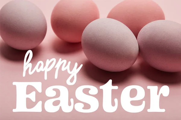 Painted pink eggs on pink surface with white happy Easter lettering — Stock Photo