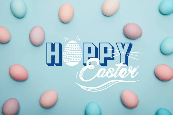 Top view of painted colorful eggs on blue background with happy Easter lettering — Stock Photo