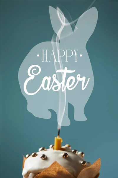 Selective focus of traditional Easter cake with fireless candle and smoke on blue background with happy easter lettering and rabbit illustration — Stock Photo