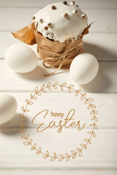 Traditional Easter cake and white chicken eggs on white wooden table with happy easter lettering — Stock Photo