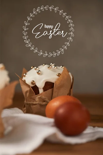 Селективный фокус традиционного пасхального торта в ремесленной бумаге и куриных яйцах на салфетке со счастливой пасхальной надписью в кругу выше — стоковое фото