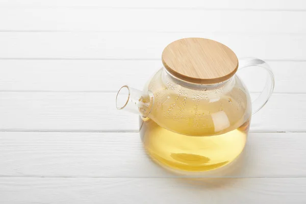 Théière en verre avec tisane bio sur table en bois blanc avec espace de copie — Photo de stock