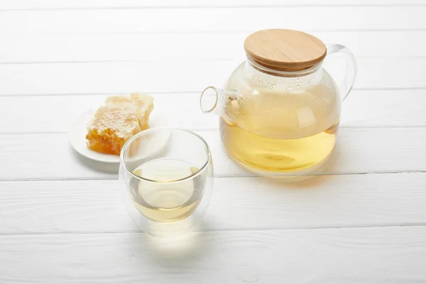 Bule com chá de ervas orgânicas, vidro e favo de mel na mesa de madeira branca — Fotografia de Stock