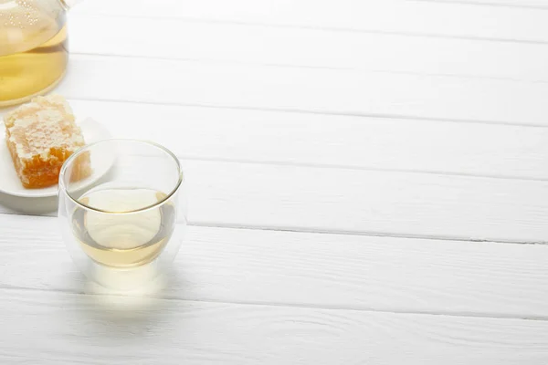 Vidro transparente com chá de ervas e favo de mel na mesa de madeira branca com espaço de cópia — Fotografia de Stock
