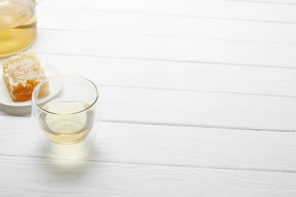 Vidrio transparente con té de hierbas y panal de abeja en mesa de madera blanca con espacio para copiar — Stock Photo