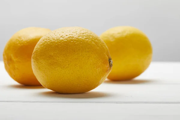 Citrons bio mûrs sur table en bois blanc isolé sur gris — Photo de stock