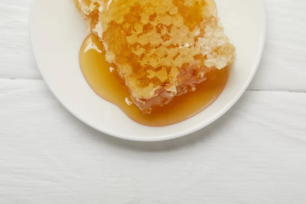 Вид зверху на тарілку зі смачною органічною медовою паличкою на білому дерев'яному столі — стокове фото