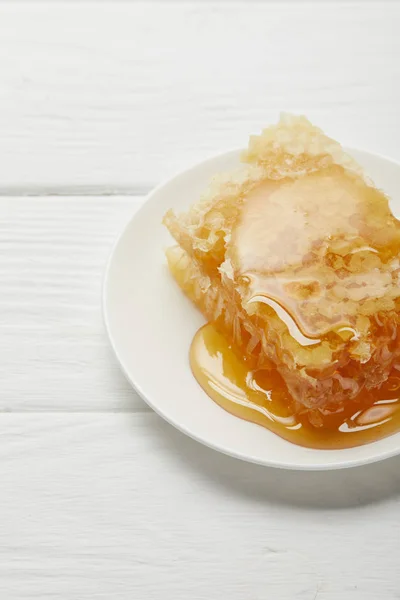 Prato com delicioso favo de mel orgânico na mesa de madeira branca — Fotografia de Stock