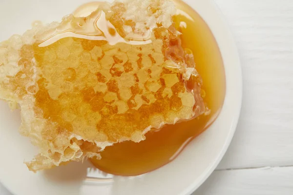 Вид зверху на тарілку зі смачною медовою паличкою на білому столі — стокове фото