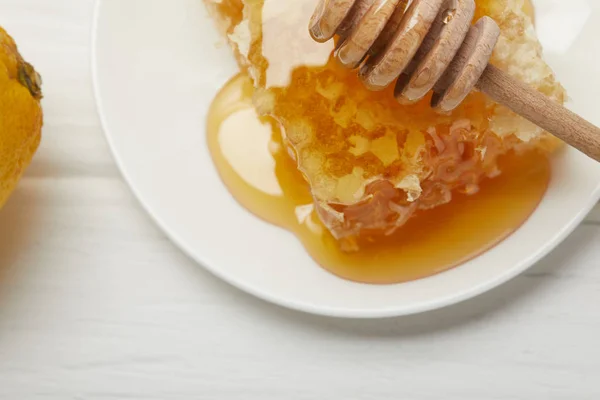 Крупним планом вид на тарілку зі смачною медовою паличкою та медовим крапельницею на білому столі — стокове фото