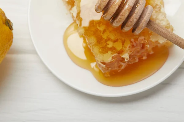 Close up view of plate with delicious honeycomb and honey dripper on white table — Stock Photo