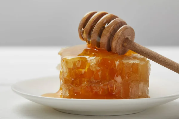 Enfoque selectivo de la placa con delicioso panal y gotero de miel aislado en gris - foto de stock