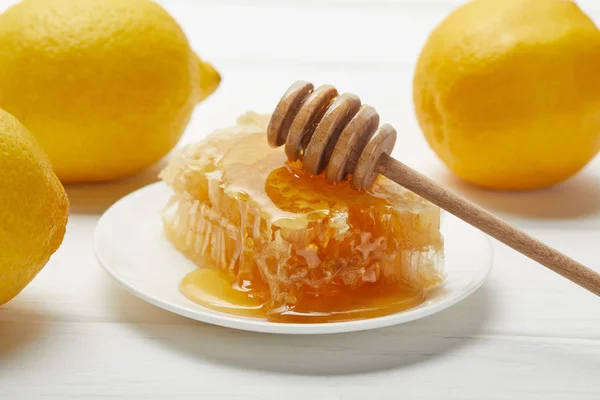 Вкусные соты, лимоны и медовая капельница на белом деревянном столе — стоковое фото