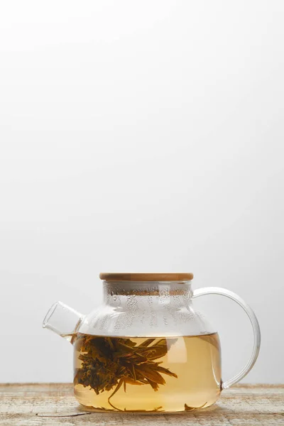 Скляний чайник з китайським квітучим чаєм на дерев'яному столі ізольовано на сірому з копією простору — стокове фото