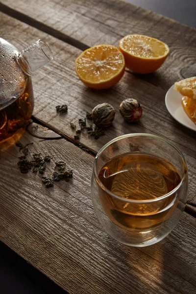 Théière transparente avec verre de thé chinois en fleurs, boules de thé et citrons sur table en bois — Stock Photo