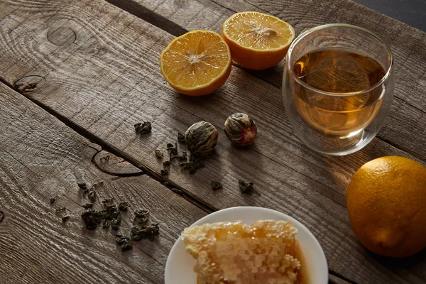 Vidro de chá tradicional chinês florescendo, limões e favo de mel na mesa de madeira — Fotografia de Stock