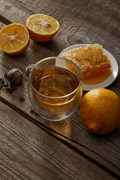 Glas chinesischen blühenden Tee, Zitronen und Honigwaben auf Holztisch — Stockfoto